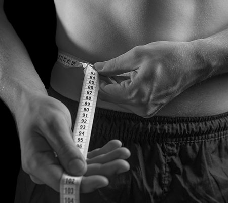 Waist measurement being taken by a man with a tape measure, following love handles liposuction for men.