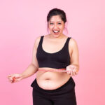 Overweight woman measuring her belly fat