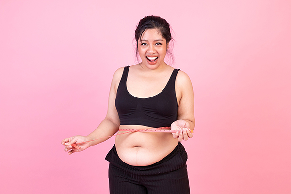 Overweight woman measuring her belly fat